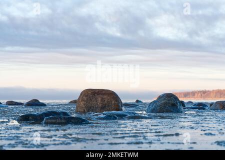 Panoramablick auf das schneebedeckte Ufer der Ostsee bei Sonnenuntergang. Eisfragmente aus der Nähe des Meeres. Stockfoto