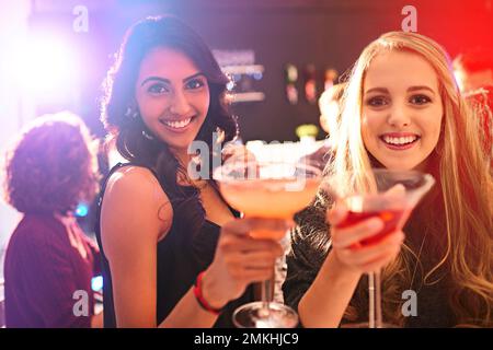 Hier, um dich zu feiern. Porträt von zwei jungen Frauen, die Cocktails auf einer Party trinken. Stockfoto