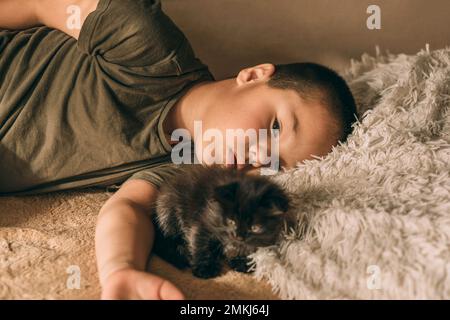 Porträt eines asiatischen Jungen, der traurig mit einem Kätzchen liegt Stockfoto