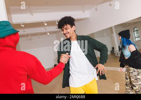 Bild von glücklichen, vielfältigen männlichen Hüftttänzern, die im Studio die Hand schütteln. Tanz, Rhythmus, Bewegung und Trainingskonzept. Stockfoto