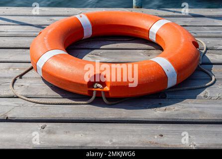Das Rettungsboot liegt auf einem hölzernen Pier. Das Konzept der Ertrinkungsersparnis auf dem Wasser. Stockfoto