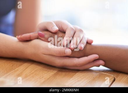 Bei mir bist du sicher. Zwei Personen, die bequem Händchen halten. Stockfoto