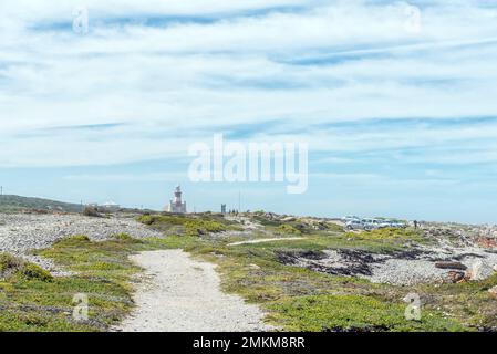 L'Agulhas, Südafrika - 21. September 2022: Blick vom südlichsten Punkt Afrikas, Cape L'Agulhas in Richtung Leuchtturm und Parkplatz. Fahrzeuge, Stockfoto