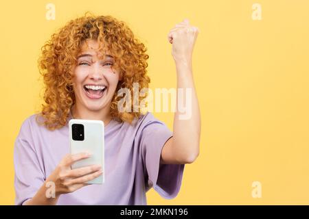 Aufgeregte Frau, die mit dem Mobiltelefon feiert Stockfoto