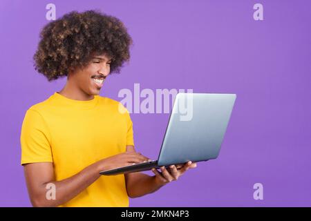 Glücklicher afrikaner, der steht und ein Notebook benutzt Stockfoto