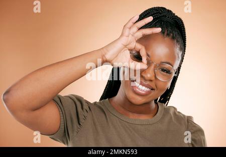 Schwarze Frau, Porträtlächeln und ok Handzeichen für perfekt, toll oder direkt vor Studiohintergrund. Glückliche afroamerikanische Frau, die vor Glück lächelt Stockfoto