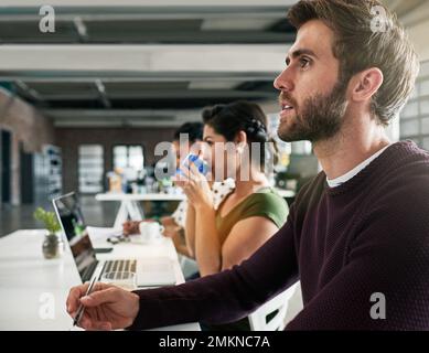 Voll und ganz in die Besprechung eingebunden. Ein Team von Kollegen, das ein Meeting in einem modernen Büro abhält. Stockfoto