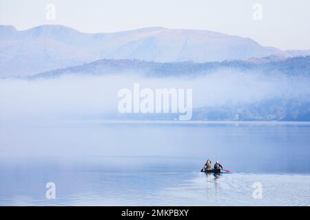 LAKE DISTRICT, GROSSBRITANNIEN - 12. OKTOBER 2010. Ein Paar paddelt mit einem Doppelkanu auf einem See, neblig am Morgen im Herbst. Coniston Water, Lake District, England, Großbritannien Stockfoto