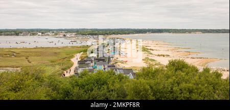 DORSET, Großbritannien - 07. Juli 2022. Strandhütten auf Hengistbury Head mit Christchurch Harbour im Hintergrund. Panoramaaussicht Stockfoto