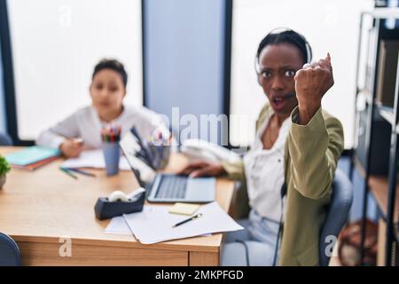 Junge Mutter, die ein Headset für Callcenter-Agenten trug, war verärgert und frustriert, schrie vor Wut, schrie verrückt, mit Wut und erhobener Hand Stockfoto