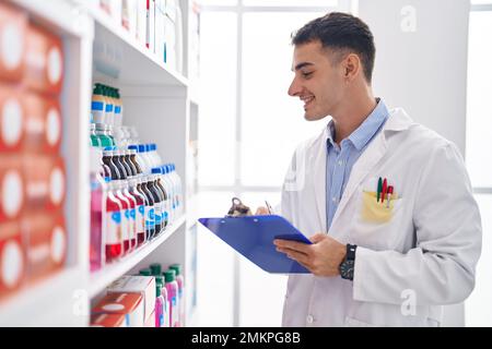 Junger hispanischer Apotheker, der auf einem Dokument in der Apotheke schreibt Stockfoto