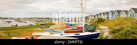DORSET, Großbritannien - 07. Juli 2022. Reihen von Booten und Strandhütten am Meer. Panoramablick auf Hengistbury Head und den Hafen von Christchurch Stockfoto