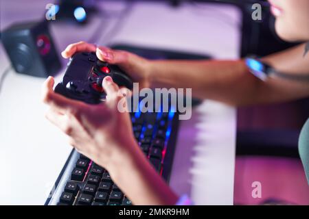 Junge blonde Frau, die Videospiele mit dem Joystick im Spielzimmer spielt Stockfoto