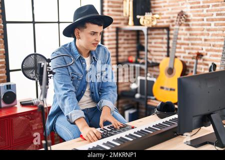 Junger nicht-binärer Musiker, der Klavier-Keyboard im Musikstudio spielt Stockfoto