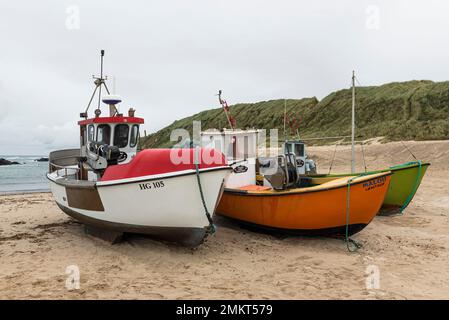 Dänemark, Nordjütland, Lönstrup: Drei farbenfrohe Fischerboote, die am Sandstrand unter einem bedeckten Himmel gezogen wurden. Stockfoto