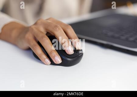 BIPOC-Frau arbeitet an einem Computer in einem Büro. Schwarze weibliche Klickerin mit drahtloser Computermaus in Nahaufnahme Stockfoto