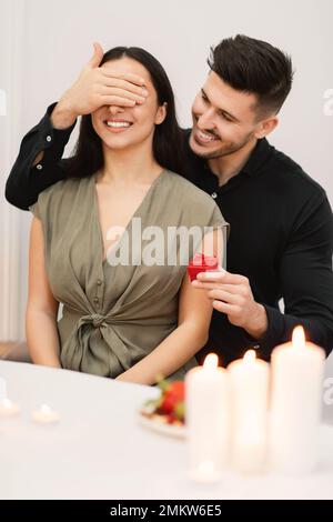 Attraktiver Brünetter, überraschende Freundin mit Geschenk Stockfoto