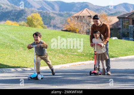 Vater nahm die Kinder mit, um auf dem Roller zu spielen Stockfoto