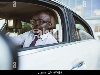 Porträt eines erfolgreichen afroamerikanischen Geschäftsmannes, der sein Auto fährt Stockfoto