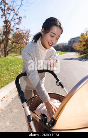 Junge Mutter schiebt einen Kinderwagen für einen Spaziergang Stockfoto