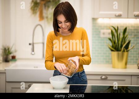 Junge Frau, die zu Hause ein gesundes Frühstück macht Stockfoto