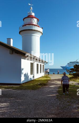 Menschen, die ein Kreuzfahrtschiff am Leuchtturm Sletterhage Fyr auf der Halbinsel Helgenæs in Djursland im Sonnenschein, Jütland, Dänemark, vorbeifahren sehen Stockfoto