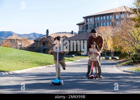 Vater nahm die Kinder mit, um auf dem Roller zu spielen Stockfoto