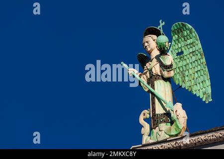 Der Erzengel Michael besiegt den Drachen, eine mittelalterliche Statue aus dem 13. Jahrhundert auf der Spitze der St. Michael Kirche in Lucca (mit blauem Himmel und Kopierraum) Stockfoto