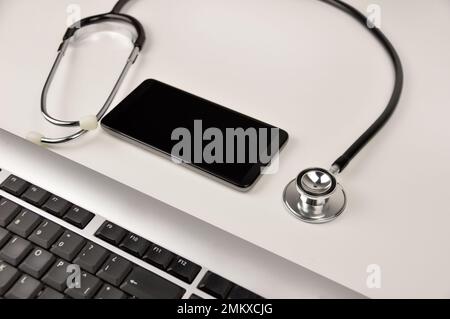 Nahaufnahme eines Smartphones, einer Tastatur und eines Stethoskops auf dem Schreibtisch eines Arztes Stockfoto