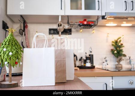 Die Lieferservice-Pakete liegen auf dem Küchentisch dekoriert für Weihnachten. Geschenke und Fertiggerichte werden geliefert und für das neue Jahr vorbereitet Stockfoto