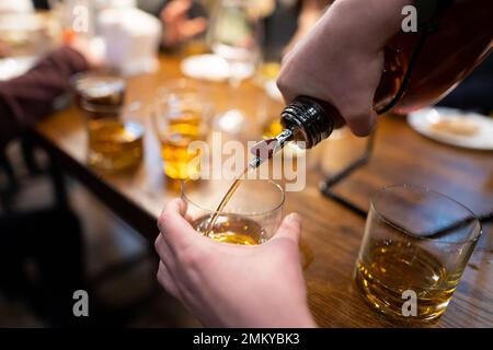 Der Barkeeper gießt Alkohol aus der Flasche Stockfoto