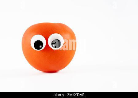 Große, sonnengereifte Tomate mit Karikaturen, die auf weißem Hintergrund gerollt sind Stockfoto