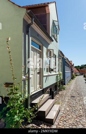 Dänemark, Jütland, Djursland, Ebeltoft: Farbenfrohe Fassaden und Klippen in den Gassen der Altstadt in der Sonne vor blauem Himmel Stockfoto