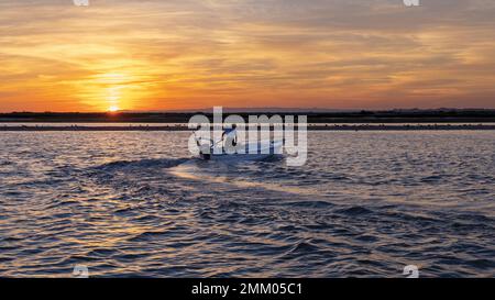 Isla Cristina, Provinz Huelva, Andalusien, Südspanien. Motorbetriebenes Außenbordboot vor dem Himmel bei Sonnenuntergang. Stockfoto