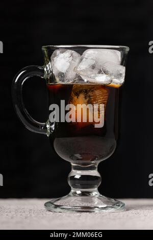 Zubereitung von kaltem Kaffee. Kaffee und Milch werden in ein Glas mit Eis gegossen Stockfoto