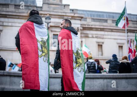 Demonstranten, die mit iranischen Flaggen umhüllt sind, nehmen an der ìSupport-iranischen Revolution Teil!î-Protest. Demonstranten trafen sich am Trafalgar Square in London, um die Frauen im Iran zu unterstützen, während sie für ihre Freiheit kämpfen. Nach dem Tod einer 22-jährigen Frau im Iran, Mahsa Amini, durch die Hände der „Moralpolizei“, weil sie ihre Haare nicht richtig vertuscht hatte, sind die Frauen des Iran auf die Straße gegangen, um ihre Freiheit zu fordern. Frauen im Iran sind gezwungen, sich an obligatorische Tarngesetze zu halten, und können sich wegen der Nichteinhaltung der Kleiderordnung mit Inhaftierung, Belästigung und Folter konfrontiert sehen. (Foto: Loredana Sangiu Stockfoto