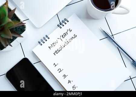 Neujahrsvorsätze auf einem Notebook mit Notebook, einer Tasse Kaffee und technischen Geräten Stockfoto