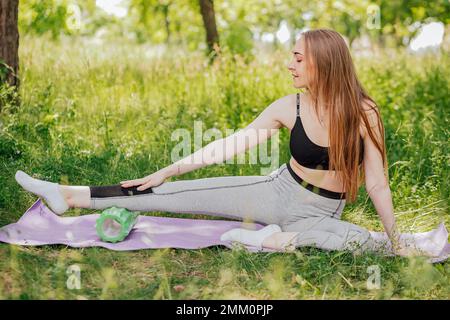 Eine attraktive junge Dame dehnt ihren Körper, um sich auf ein morgendliches Workout auf einem Freifeld vorzubereiten. Stockfoto