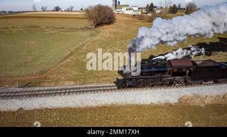 Ein restaurierter antiker Dampferzug, der an einem sonnigen Herbsttag durch die Landschaft reist, aus der Vogelperspektive Stockfoto