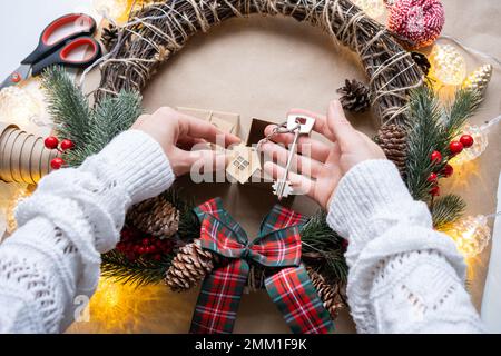 Schlüssel zum Haus mit Schlüsselanhänger auf gemütlichem Zuhause in Geschenkbox mit Weihnachtsdekor-Verpackung. Pack ein Geschenk für Neujahr, Weihnachten. Gebäude, Projekt, Umzug nach Stockfoto