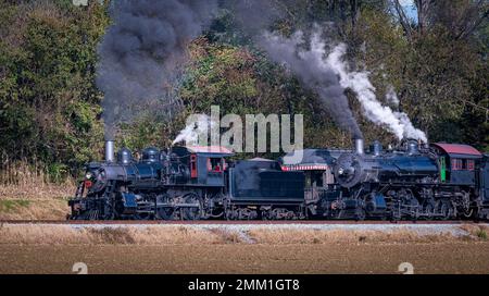 Ein Blick auf zwei Dampflokomotiven, „Blowing Smoke and Steam“, die an einem sonnigen Tag aufeinander zugehen Stockfoto