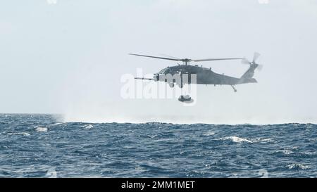 Ein HH-60G Pave Hawk, der der 33. Rescue Squadron zugewiesen wurde, senkt ein Kampfflugzeugs, das Kautschuk überführt, in den Pazifischen Ozean, 13. September 2022. Die CRRC, in diesem Szenario auch als Tethered Ente bekannt, wird ins Wasser fallen gelassen und von pararescuemen aufgepumpt, sobald sie das Flugzeug verlassen. Stockfoto