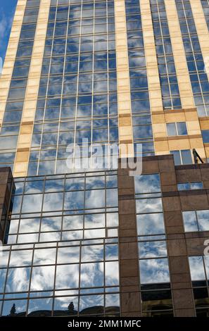 NYC: 420 Fifth Avenue spiegelt den Himmel in ihrem blau getönten Gittergitter wider; Schächte aus beigefarbenem Granit betonen die Höhe des 30-stöckigen Turms. Stockfoto