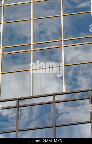 NYC: 420 Fifth Avenue spiegelt den Himmel in ihrem blau getönten Gittergitter wider; Schächte aus beigefarbenem Granit betonen die Höhe des 30-stöckigen Turms. Stockfoto