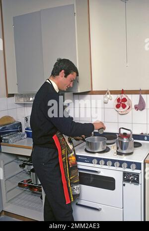 Carl XVI Gustaf, König von Schweden. Geboren am 30. april 1946. Als Kronprinz in seiner Studentenwohnung und Küche, während er in Uppsala studiert. Er steht neben dem Küchenherd und trägt eine Schürze und gibt vor, etwas zu kochen, aber es gibt kein Essen im Kochtopf. 1968 Stockfoto