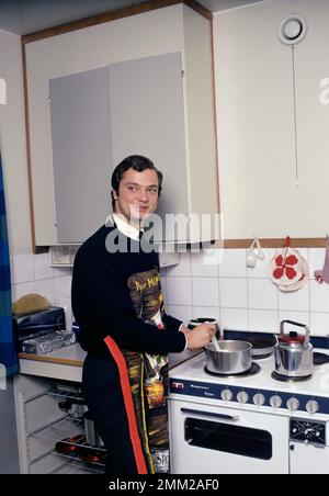 Carl XVI Gustaf, König von Schweden. Geboren am 30. april 1946. Als Kronprinz in seiner Studentenwohnung und Küche, während er in Uppsala studiert. Er steht neben dem Küchenherd und trägt eine Schürze und gibt vor, etwas zu kochen, aber es gibt kein Essen im Kochtopf. 1968 Stockfoto