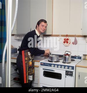 Carl XVI Gustaf, König von Schweden. Geboren am 30. april 1946. Als Kronprinz in seiner Studentenwohnung und Küche, während er in Uppsala studiert. Er steht neben dem Küchenherd und trägt eine Schürze und gibt vor, etwas zu kochen, aber es gibt kein Essen im Kochtopf. 1968 Stockfoto