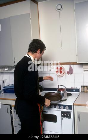 Carl XVI Gustaf, König von Schweden. Geboren am 30. april 1946. Als Kronprinz in seiner Studentenwohnung und Küche, während er in Uppsala studiert. Er steht neben dem Küchenherd und trägt eine Schürze und gibt vor, etwas zu kochen, aber es gibt kein Essen im Kochtopf. 1968 Stockfoto