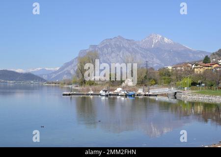 Wunderschöner Panoramablick auf den Garlatersee in Lecco vom Comer See in Italien. Kleiner Pier für Motorboote im Vordergrund. Stockfoto