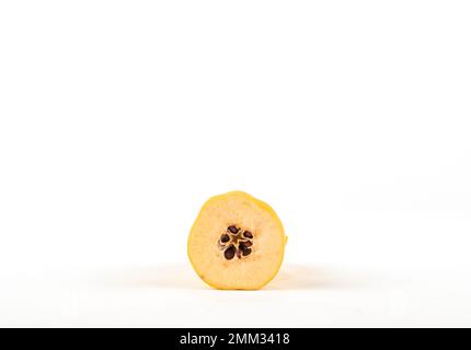 Die Hälfte der Quitten mit Samen ist auf weißem Hintergrund. Quitten-Samen mit isoliertem weißem Hintergrund auf der Platte. Stockfoto